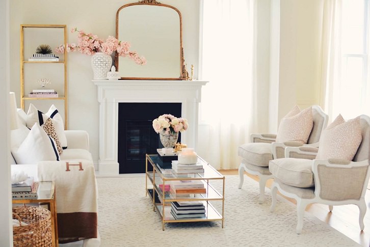 مبل های کلاسیک با رومبلی های بژ که پایه های جلوی آن روی فرش سفید کرم در پذیرایی با آینه و شومینه گچی قرار دارد